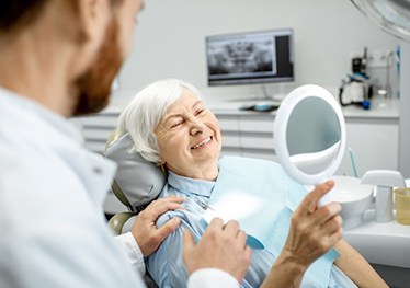 a patient checking her smile with a mirror