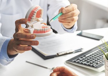 a dentist showing a patient a model of teeth